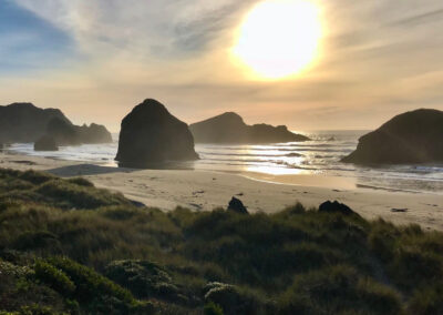 grassy dune beach sunset behind huge rock columns in the breakers